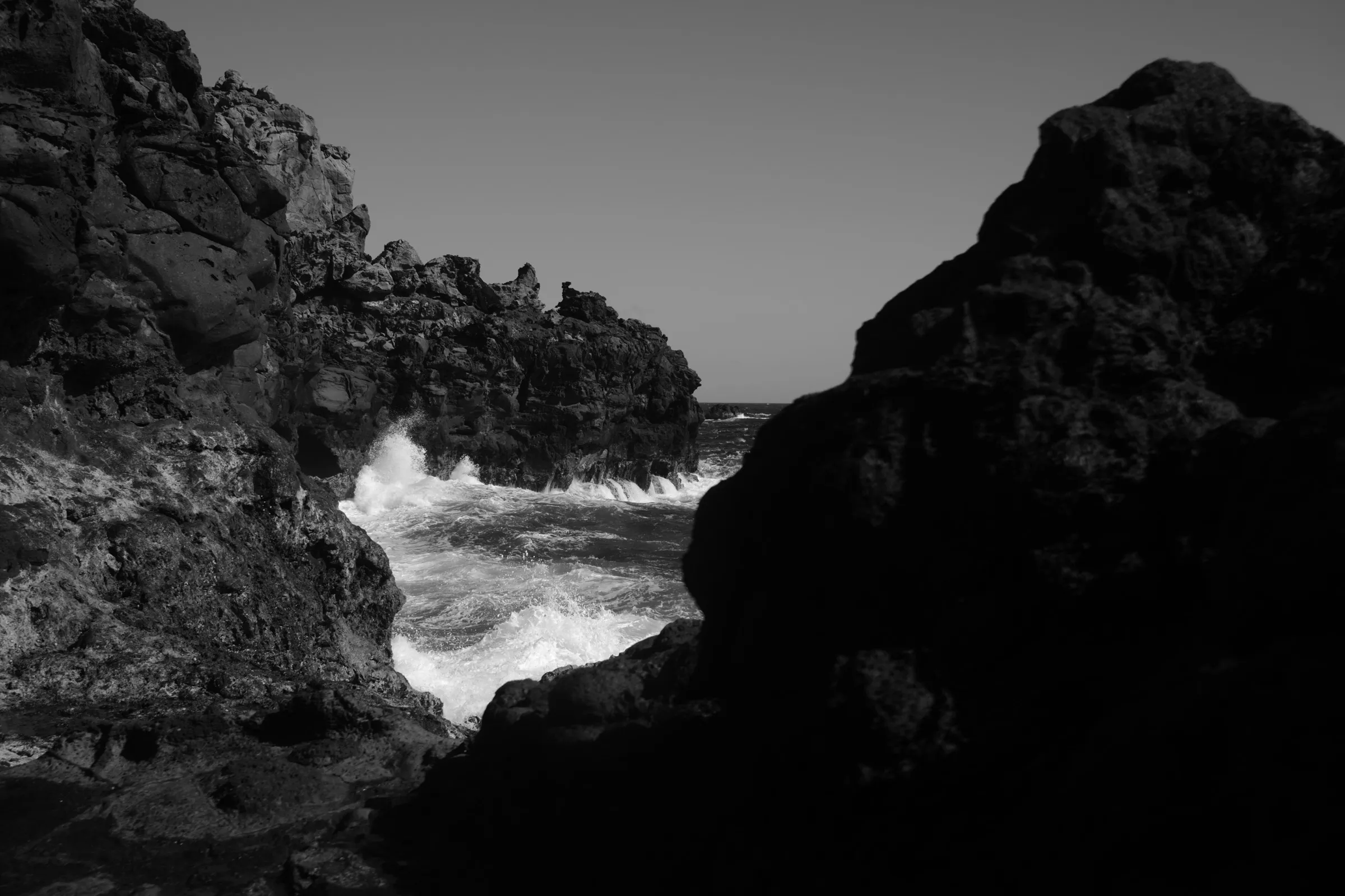 Rocky coastal cliffs with breaking waves, black and white