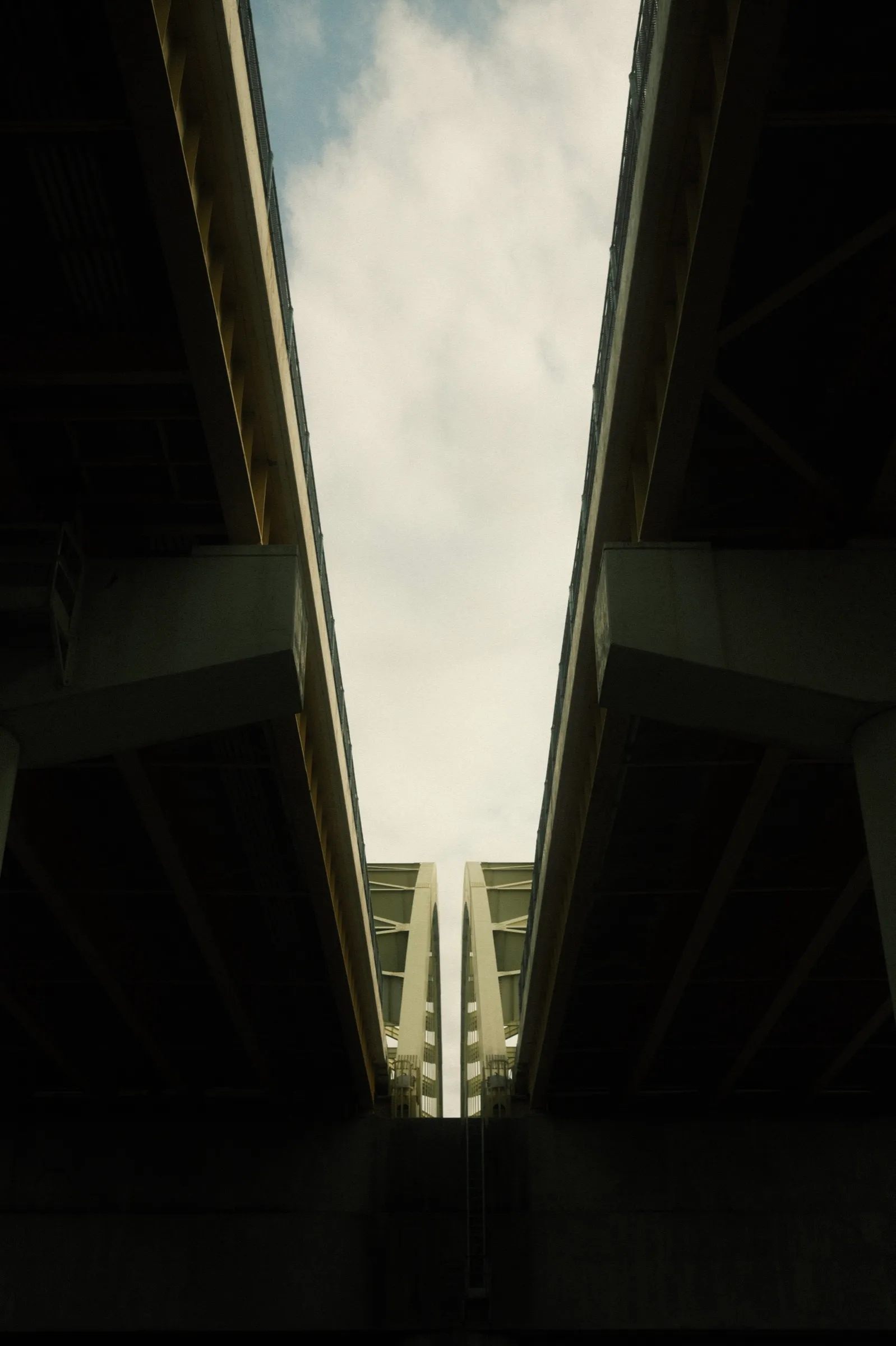 Looking up between twin parallel bridges into the open sky