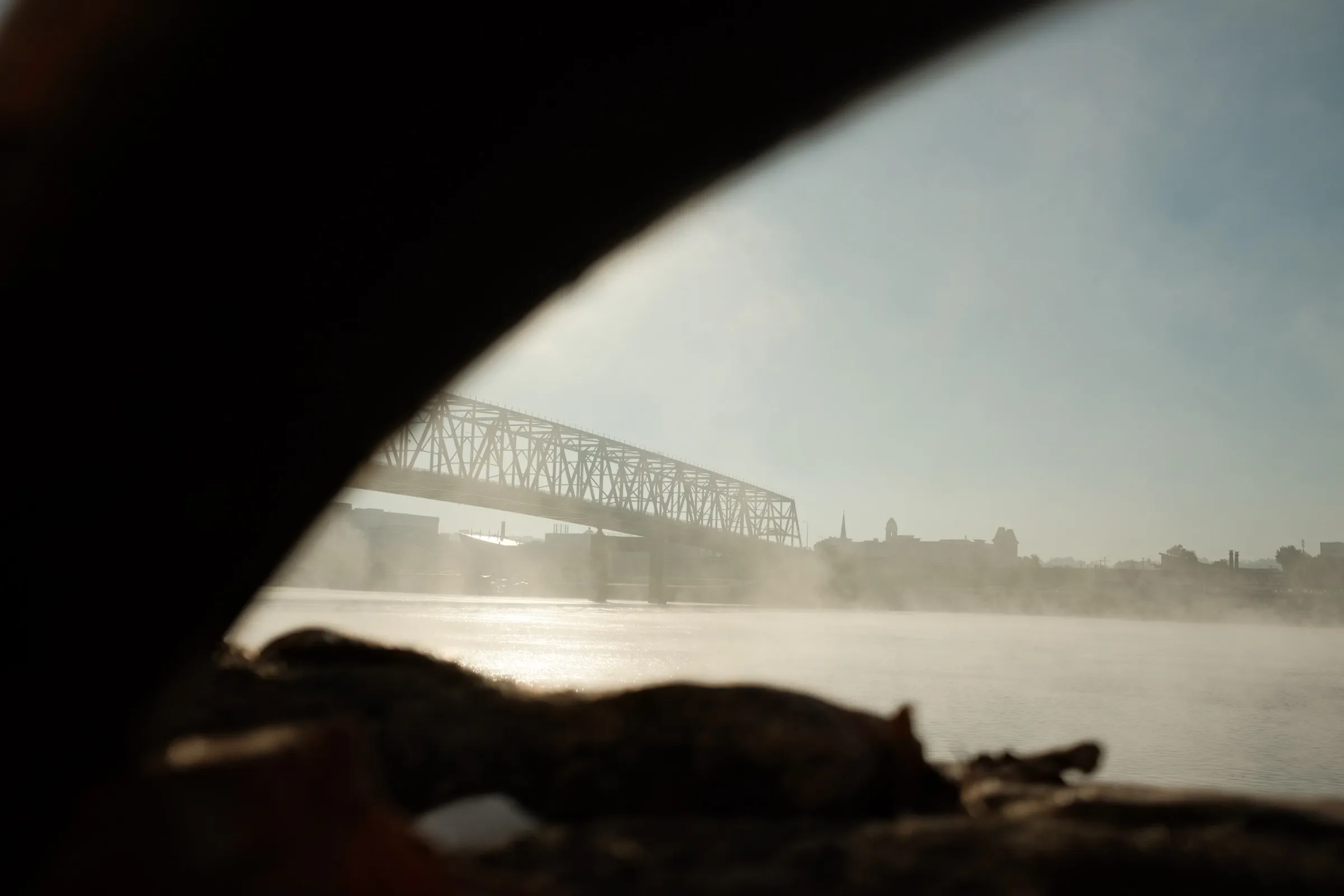 Ohio River at dawn with rolling mist and bridge silhouette
