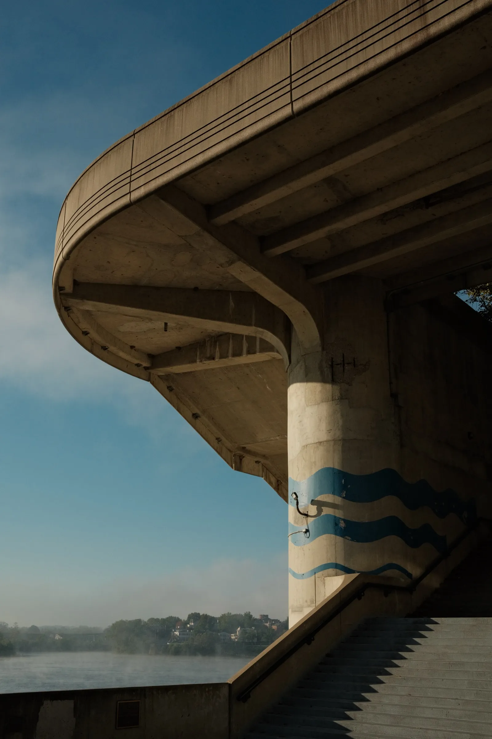 Concrete bridge archway against blue sky with a painted wave mural