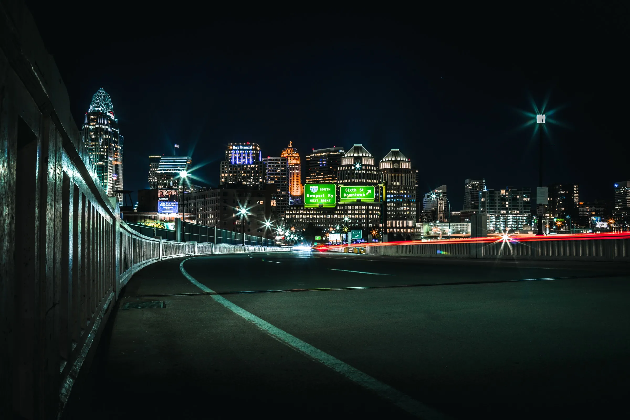 Cincinnati skyline at night with highway light trails curving in