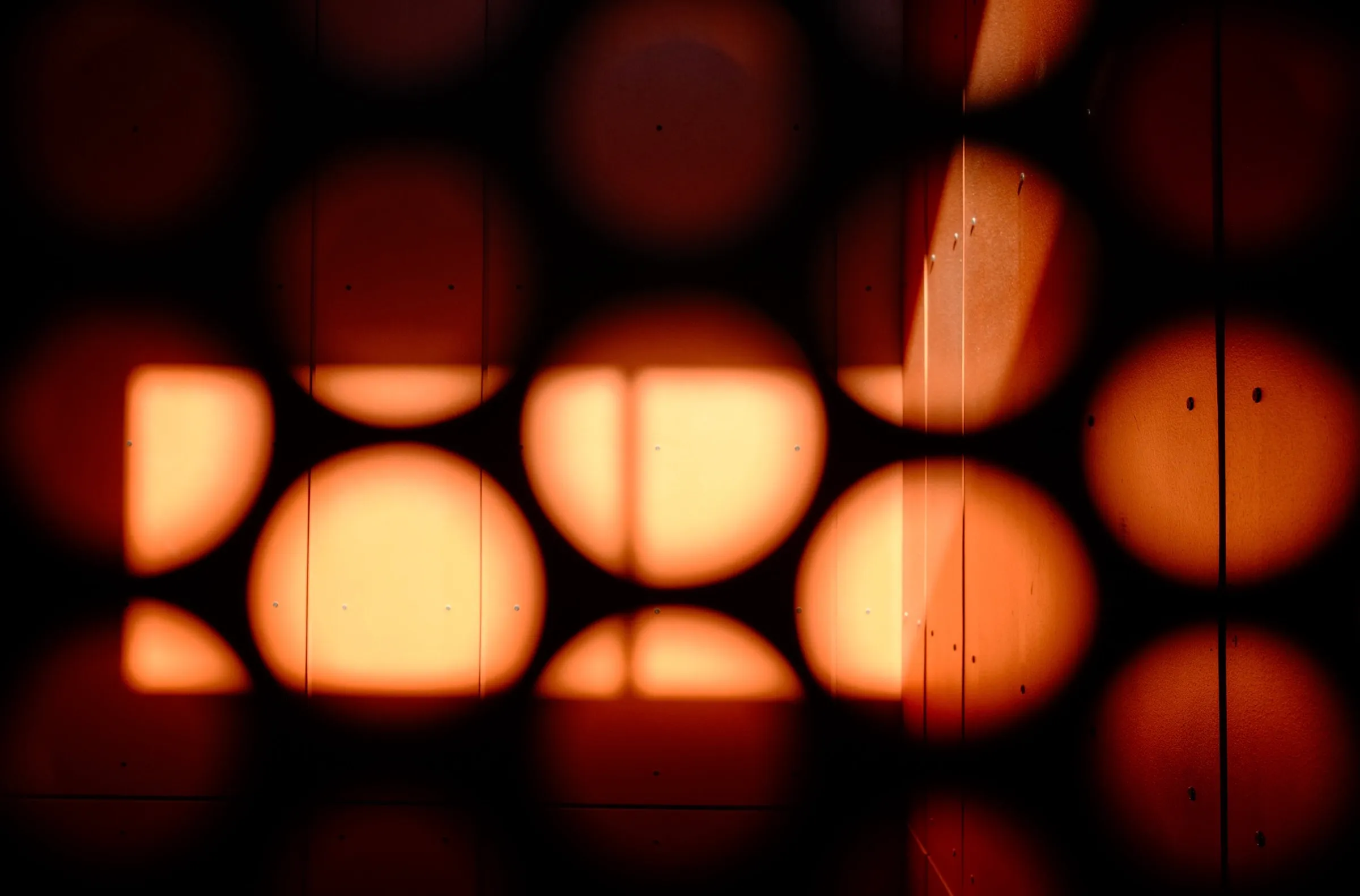 Warm amber light through perforated library architecture