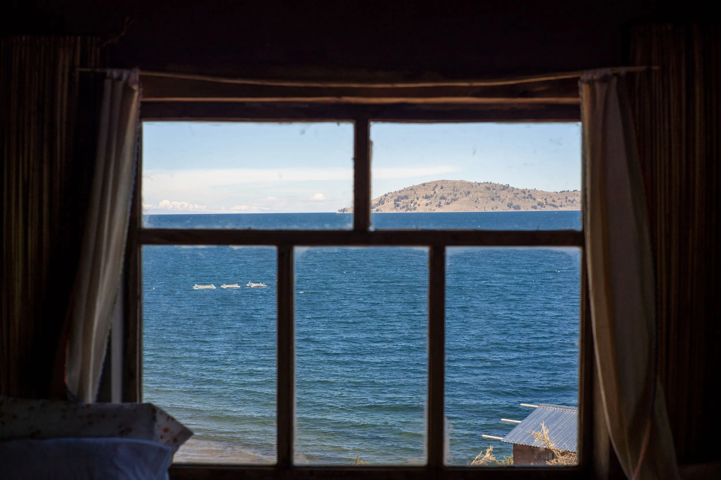 Lake Titicaca and distant island viewed through a window with fishing boats